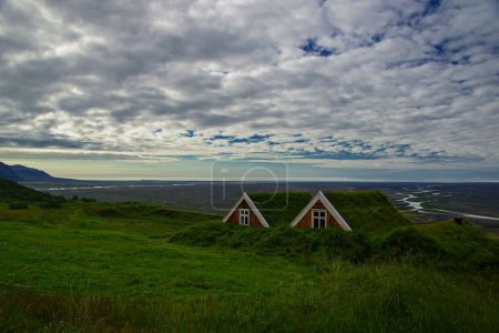 Foto de Un paisaje de césped islandés en prados con cielo azul nublado en el horizonte - Imagen libre de derechos