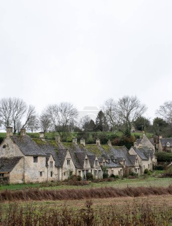 Photo for A vertical shot of a row of the historic quintessential Cotswold cottages in Bibury, England - Royalty Free Image