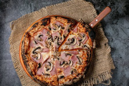 Téléchargez les photos : Vue de dessus d'une pizza napolitaine cuite dans un four à bois, servie sur une nappe de paille - en image libre de droit