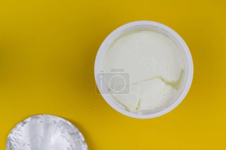 Téléchargez les photos : Un yaourt naturel dans une tasse en plastique en fond jaune - en image libre de droit