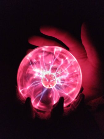 Téléchargez les photos : Un gros plan d'un globe plasma lumineux avec une main qui le touche. - en image libre de droit