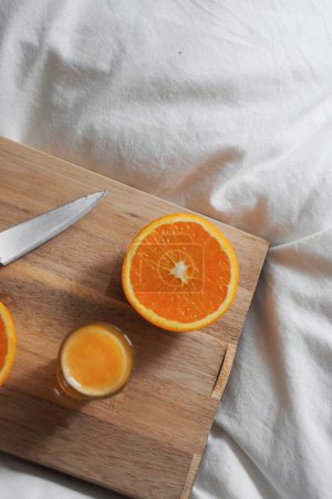 Foto de Un primer plano de naranja cortada a bordo en la cama blanca - Imagen libre de derechos