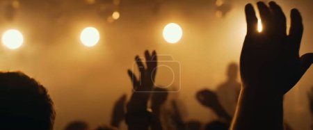 Téléchargez les photos : Une silhouette des mains levées lors d'un grand événement avec un fond flou - en image libre de droit