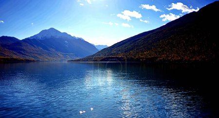 Foto de Una vista panorámica de un lago contra las montañas en un día soleado - Imagen libre de derechos