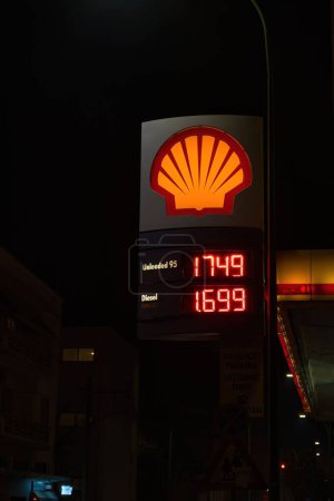 Foto de Letrero iluminado con una lista de precios de combustibles líquidos en la conocida marca Shell - Imagen libre de derechos