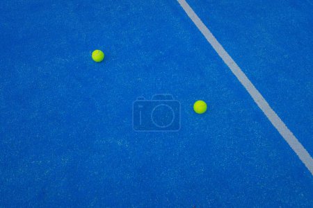 Foto de Dos pelotas de pádel en una cancha de césped artificial azul cerca de la línea central. Pista de pádel - Imagen libre de derechos