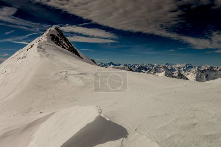 Foto de Un hermoso disparo de montañas nevadas contra un cielo azul en un día soleado - Imagen libre de derechos