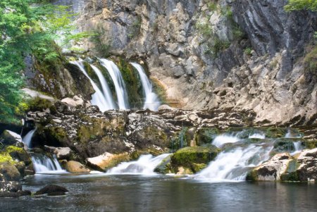 Téléchargez les photos : Un long plan d'exposition de la cascade qui descend dans les roches moussues de la forêt - en image libre de droit