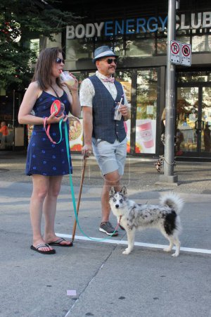 Téléchargez les photos : Un couple joyeux et élégant dans la rue Granville avec leur animal de compagnie et des boissons à Vancouver, Canada - en image libre de droit