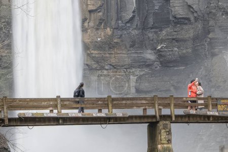 Téléchargez les photos : Ulysses, NY États-Unis 19 mars 2022 Des gens debout sur un pont prenant en compte les chutes d'eau au parc d'État de Taughannock Falls près d'Ithaca NY. - en image libre de droit