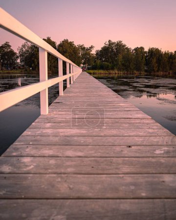 Foto de Un plano vertical de un largo embarcadero de madera durante una puesta de sol rosa en Nueva Gales del Sur, Australia - Imagen libre de derechos