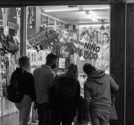 Photo for A greyscale of a family looks to the goods inside a clothes store - Royalty Free Image