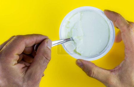 Photo for A natural yogurt in plastic cup in yellow background - Royalty Free Image