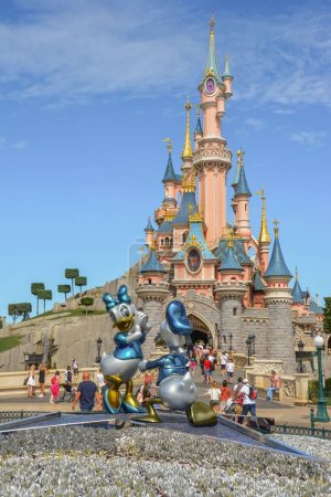 Téléchargez les photos : Un plan vertical de la vue sur Disneyland avec un château de conte de fées derrière la statue de Donald canard et marguerite canard à Paris, France - en image libre de droit