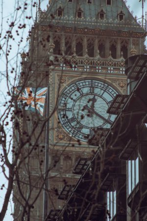 Foto de El Big Ben en Londres, Reino Unido con la bandera de Gran Bretaña ondeando en el viento a su lado - Imagen libre de derechos