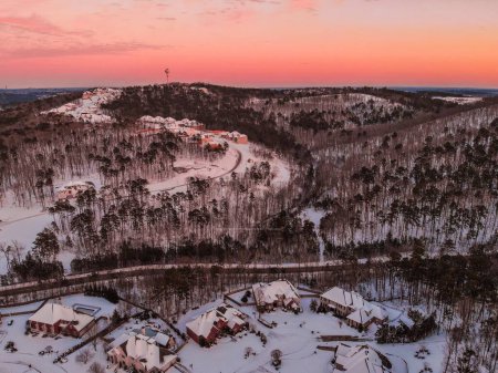 Téléchargez les photos : Vue aérienne d'une forêt couverte de neige lors d'un coucher de soleil rose - en image libre de droit