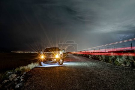 Téléchargez les photos : Vue latérale d'une Ford F150 garée dans la rue lors d'un tir de tempête en longue exposition - en image libre de droit