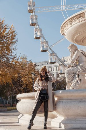 Foto de Una imagen vertical de una atractiva mujer posando frente a la noria de Budapest durante el otoño en Budapest, Hungría - Imagen libre de derechos