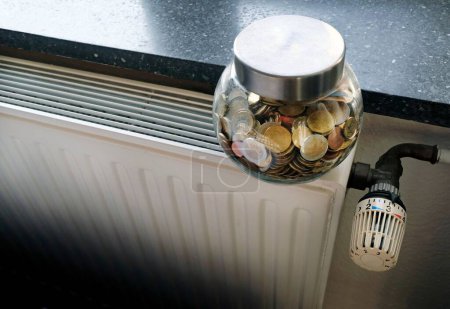 Photo for A closeup of a jar full of coins on a heating radiator - Royalty Free Image