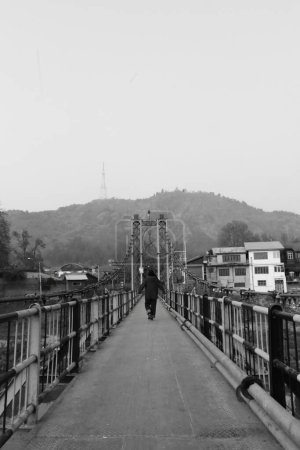 Téléchargez les photos : Plan vertical d'un homme sur un pont en niveaux de gris - en image libre de droit