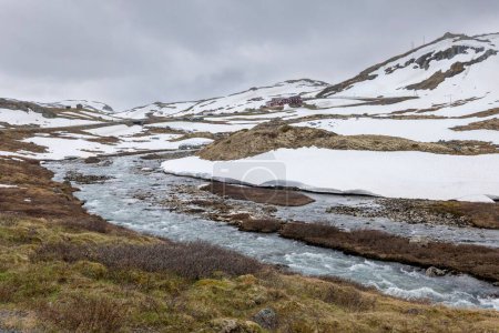 Téléchargez les photos : Un beau plan de ruisseau coulant sur la vallée de Visladen près des montagnes à Piterstulen, Jotunheimen, Norvège - en image libre de droit