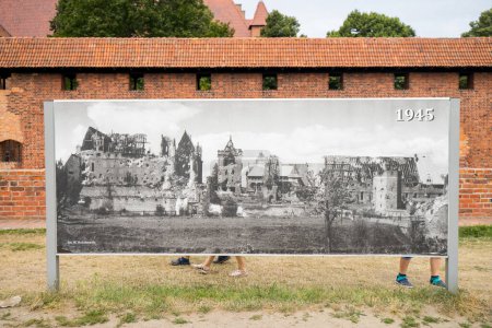 Téléchargez les photos : Une planche avec une photo en niveaux de gris, montrant la vue sur le château teutonique détruit à Malbork, en Pologne, avec un mur de briques en arrière-plan - en image libre de droit