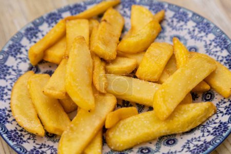 Téléchargez les photos : Un gros plan de pommes de terre jaunes frites dans une assiette bleue - en image libre de droit