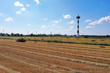 Foto de Una vista de la granja con un faro y campo segado, molinos de viento en el horizonte - Imagen libre de derechos
