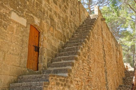 Téléchargez les photos : Une vue des escaliers devant une vieille porte en bois dans un mur de pierre à Denia, Espagne - en image libre de droit
