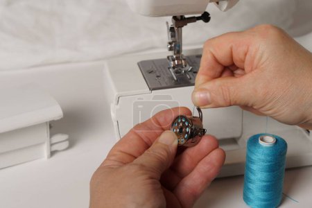 Téléchargez les photos : Close-up of a woman's hands putting blue thread on a sewing machine - en image libre de droit