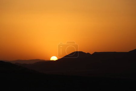 Téléchargez les photos : Silhouettes de collines avec un coucher de soleil orange en arrière-plan - en image libre de droit