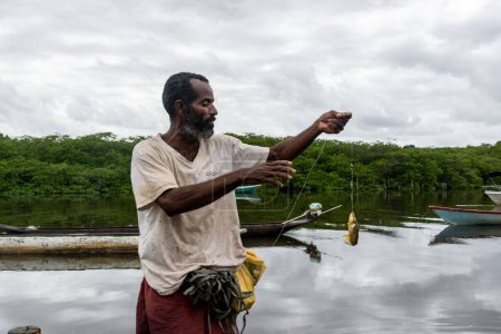 Téléchargez les photos : Pêcheur tenant ligne de pêche avec du poisson à l'hameçon. Ville d'Aratuipe, Bahia, Brésil. - en image libre de droit