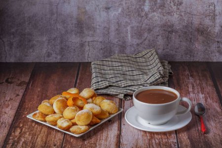 Foto de Rosquillas caseras con azúcar y chocolate caliente en una taza blanca sobre una mesa de madera - Imagen libre de derechos