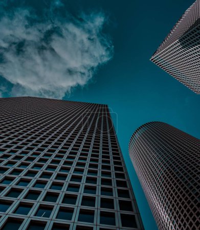 Foto de Un ángulo bajo de rascacielos modernos con exterior de cristal bajo el cielo azul - Imagen libre de derechos