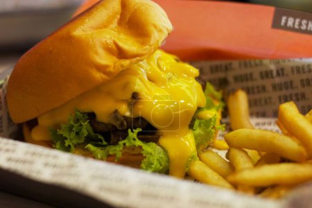 Foto de Un primer plano de una hamburguesa con queso y papas fritas - Imagen libre de derechos