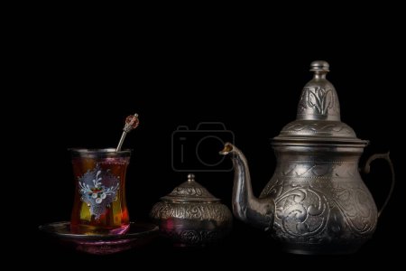 Photo for Tea cup decorated with teapot and metal sugar bowl isolated on black background - Royalty Free Image