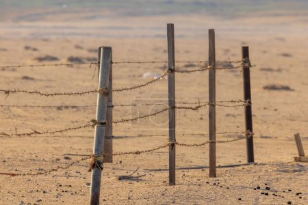 Foto de La cerca de alambre de púas en un desierto arenoso - Imagen libre de derechos