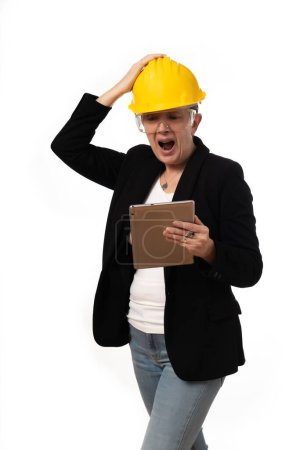 Téléchargez les photos : Une femme ingénieur regardant avec colère la tablette sur fond blanc - en image libre de droit