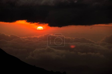 Téléchargez les photos : Une belle vue sur les nuages denses et le soleil lors d'un coucher de soleil rouge dans le ciel un concept rêveur - en image libre de droit