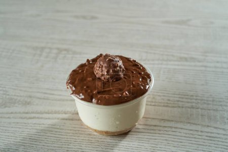 Foto de Un primer plano de la taza de pastel de queso con una superficie de crema de chocolate y caramelos de chocolate sobre un fondo de madera - Imagen libre de derechos