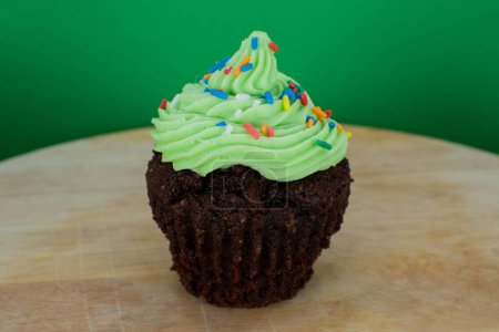 Foto de Un primer plano de cupcake de chocolate con glaseado verde en el fondo verde - Imagen libre de derechos
