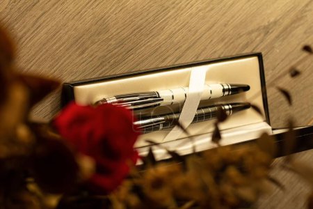Téléchargez les photos : Un gros plan du stylo de marque Montblanc et du stylo bille posés sur une table avec une rose - en image libre de droit