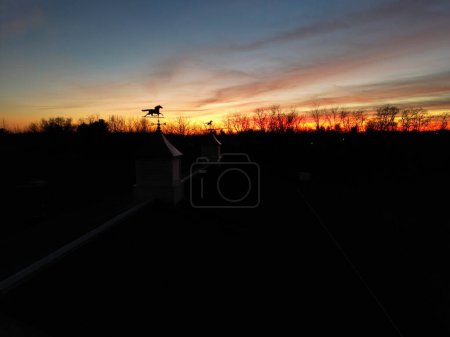 Téléchargez les photos : La silhouette des girouettes à cheval sur les coupoles et les arbres contre le ciel orange-rouge au coucher du soleil - en image libre de droit