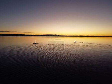 Foto de Un amanecer sobre el paisaje marino con montañas haciendo una línea oscura en el fondo - Imagen libre de derechos