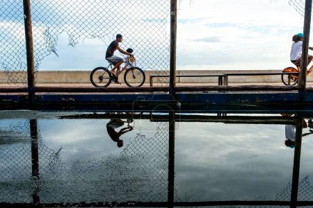 Foto de Ciclistas pasando por la orilla de la playa de Río Vermelho en la ciudad de Salvador, Bahía, durante la tarde. - Imagen libre de derechos
