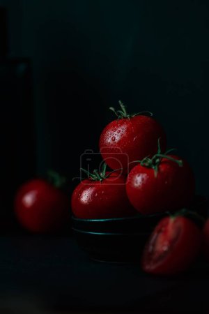 Foto de Una toma vertical de tomates rojos frescos y húmedos sobre un fondo oscuro - Imagen libre de derechos