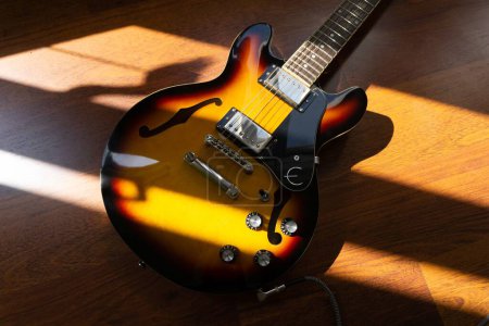 Téléchargez les photos : Une vue de dessus d'une guitare semi-acoustique couverte de lumière du soleil - en image libre de droit