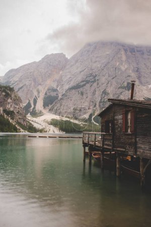 Téléchargez les photos : Plan vertical d'un vieux bâtiment en bois au bord d'un lac sur fond de collines rocheuses à couper le souffle - en image libre de droit