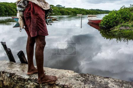 Téléchargez les photos : Partie inférieure d'un pêcheur jetant un appât dans la rivière contre la forêt verte. Ville d'Aratuipe, Brésil. - en image libre de droit