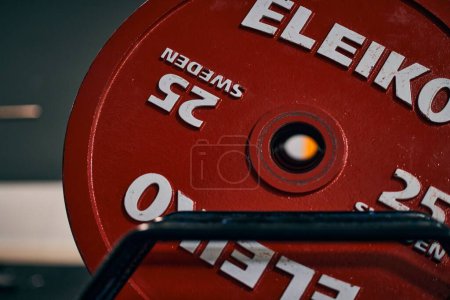 Photo for A closeup shot of a red weight plate of 25 kilograms on the stand in the powerlifting gym - Royalty Free Image